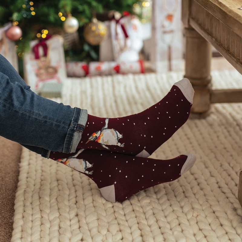 Calze natalizie da uomo decorate con pinguino con papillon su sfondo bordeaux con neve
